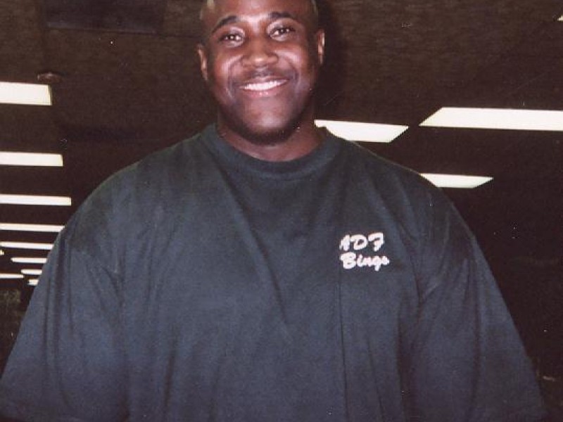 A man in a black shirt smiles at the camera