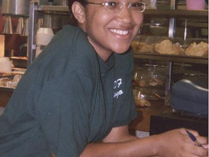A woman smiles from behind a counter 