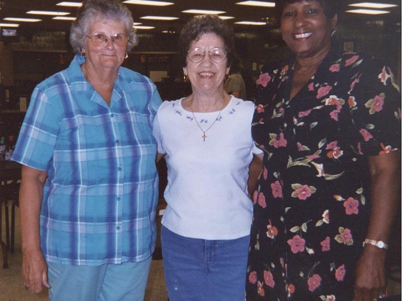 three women stand and smile side by side