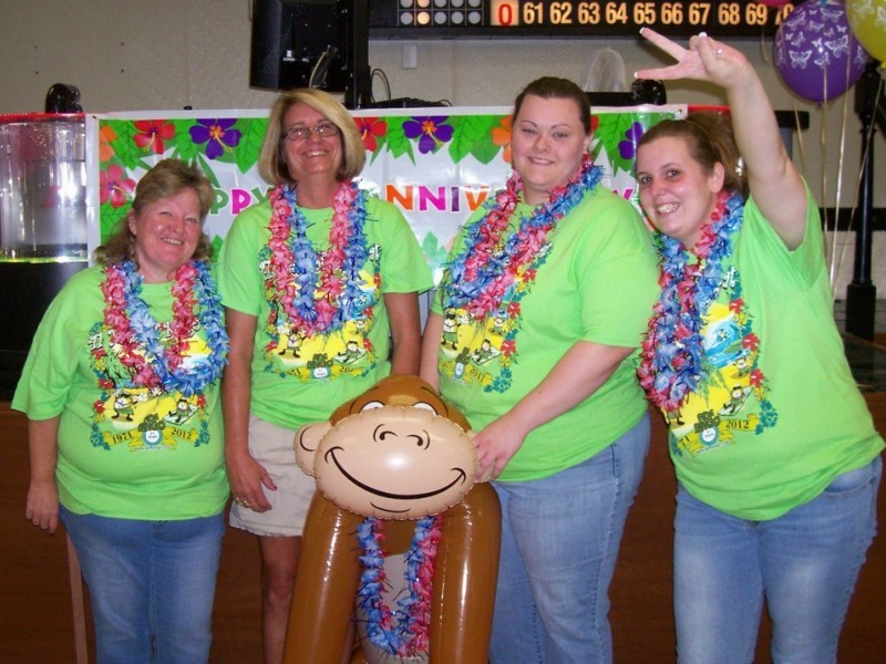 group of women in leis hold inflatable monkey