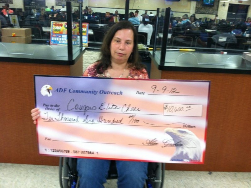 woman in wheelchair holds giant check