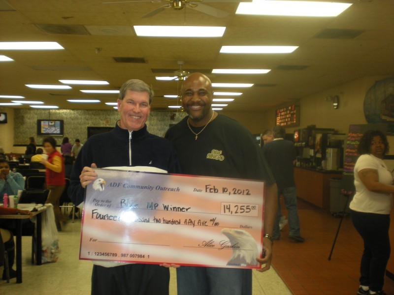men hold giant check with flack background