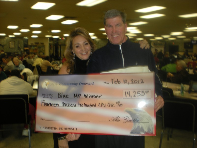 man and wife smile while holding huge check
