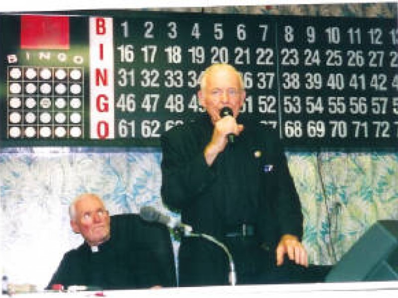a man dressed in black announcing bingo numbers