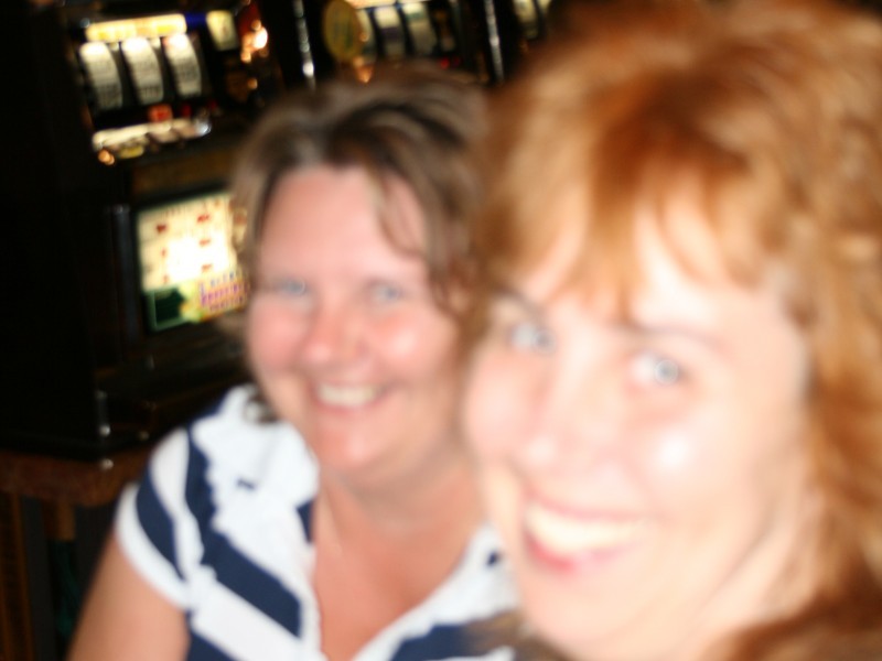 two women smile in front of slot machines