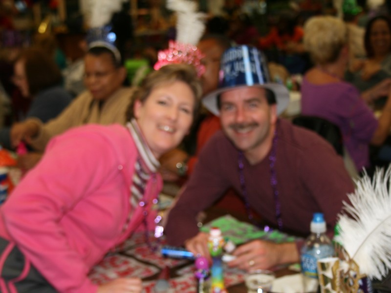 man and woman lean across table at new years celebration for photo