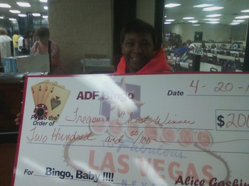 woman smiles while holding check prize winnings