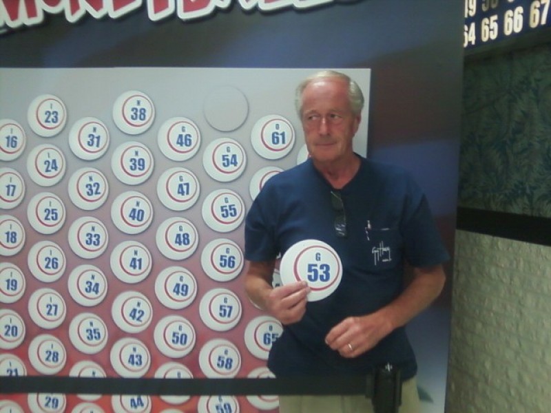 smiling man holds a money ball #53 in front of wall of money balls