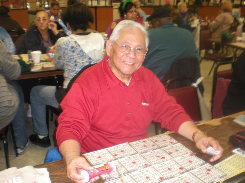 man wearing red shirt smiles while playing bingo